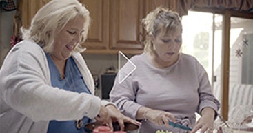 Thumbnail of two women in a kitchen, for the Ibrance (palbociclib) Ambassadors video, Commitment Without Question, featuring Julie, an Ibrance caregiver ambassador
